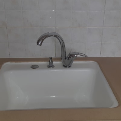 כיור מטבח עם ברז כסוף על רקע אריחים