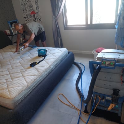 אדם מנקה מזרן עם מכונת ניקוי וציוד מקצועי