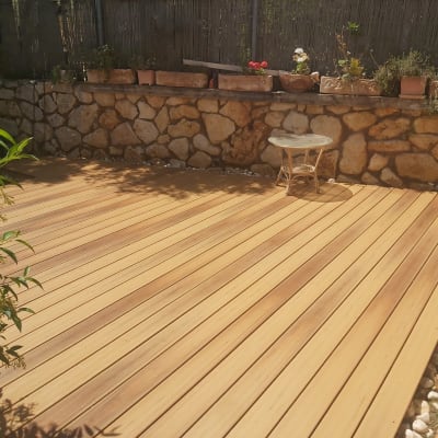 דק עץ בגינה עם שולחן קטן וצמחים