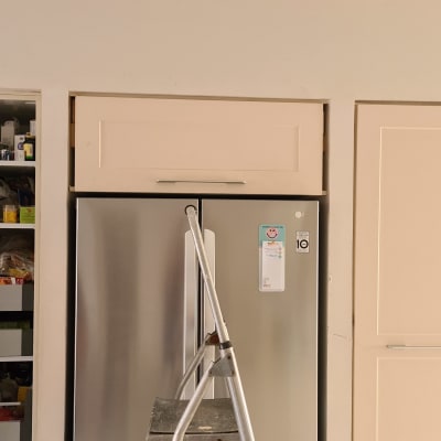 אדם פותח ארון מטבח ליד סולם קטן