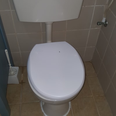 אסלה עם מיכל הדחה וצינור מים מחובר