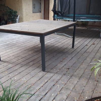 שולחן עץ על דק עץ בגינה עם צמחייה מסביב