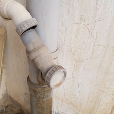 צינור פלסטיק עם מחבר זוויתי על קיר