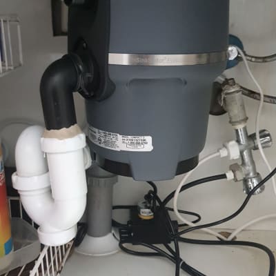 מכשיר טוחן אשפה מתחת לכיור עם צינורות חיבור