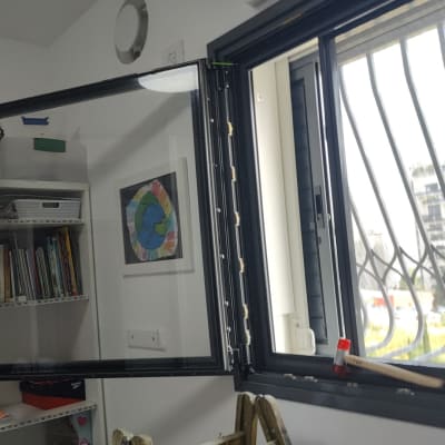 חלון פתוח עם תריסים שחורים ומסגרת מתכת