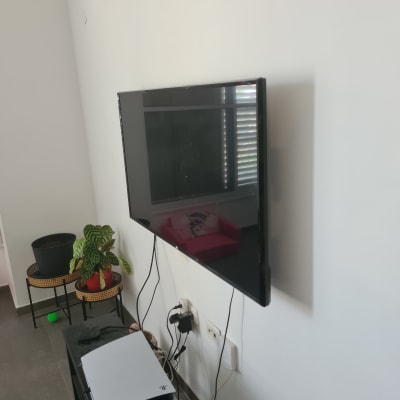 טלוויזיה תלויה על הקיר עם כבלים חשמליים