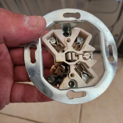 שקע חשמלי עם חוטים שרופים ביד חשמלאי