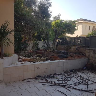 חצר עם צמחייה, אדמה וכלי עבודה מפוזרים