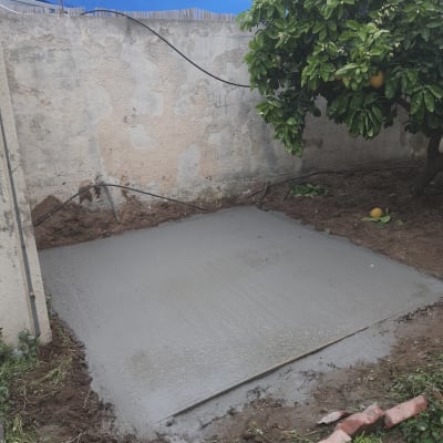 משטח בטון טרי בחצר עם קיר בטון