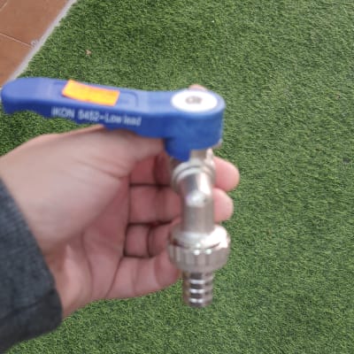 ברז מתכת עם ידית כחולה ביד של אדם