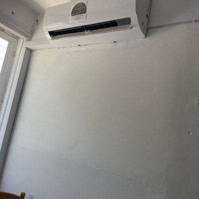 מזגן מותקן על קיר לבן ליד חלון פתוח