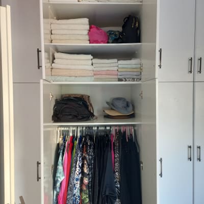 ארון בגדים מסודר עם מגבות ובגדים תלויים