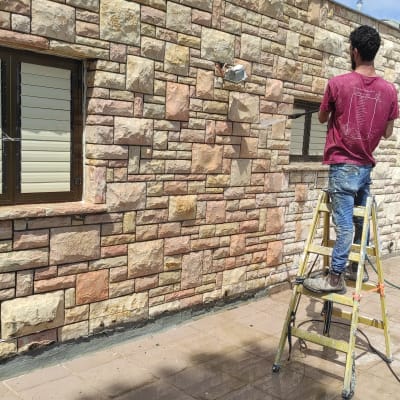 אדם על סולם אוטם קיר אבן עם חומר איטום