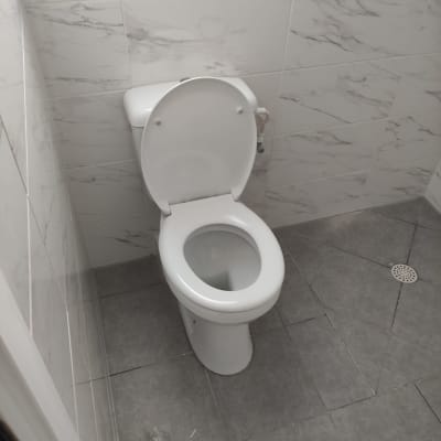 אסלה לבנה בחדר אמבטיה עם רצפת אריחים אפורה