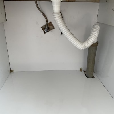 צינור פלסטיק מתחת לכיור עם חיבורי מתכת