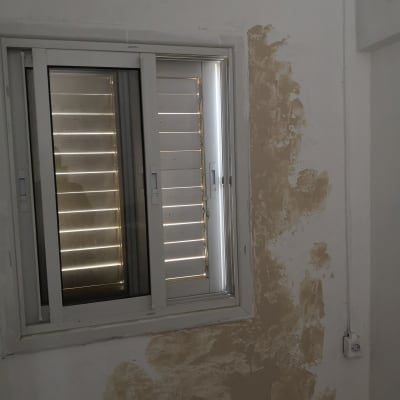 קיר עם טיח מתקלף ליד חלון ותריסים