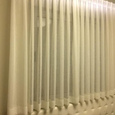 וילון לבן תלוי על חלון בחדר