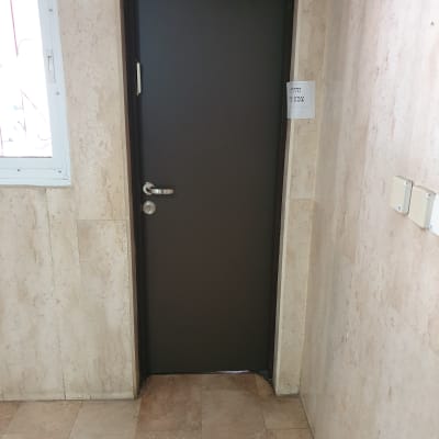 דלת מתכת כהה עם ידית כסופה וקיר אבן