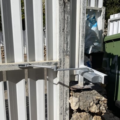 מנגנון סגירה אוטומטי על שער מתכת לבן