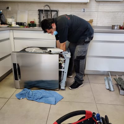 טכנאי מתקן מדיח כלים במטבח עם כלי עבודה