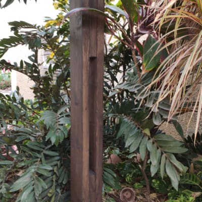 עמוד עץ כהה בגינה עם צמחייה מסביב