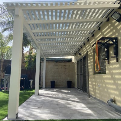 פרגולה לבנה מעץ בחצר עם דשא סינתטי