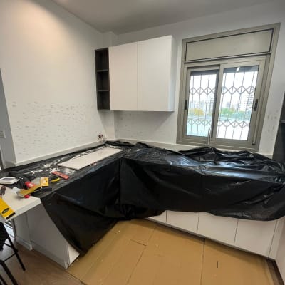 מטבח בשיפוץ עם כיסוי ניילון וכלי עבודה על השיש