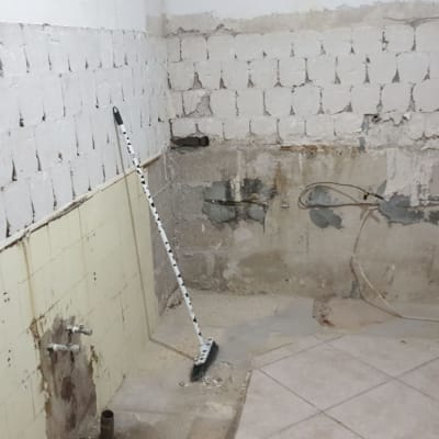 קיר חשוף עם בלוקים, מטאטא, חוטי חשמל חשופים