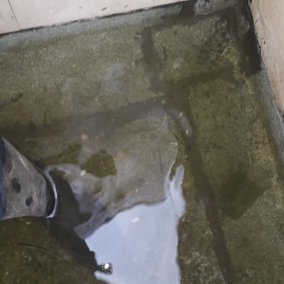 מגף של אינסטלטור עומד במים על רצפה רטובה