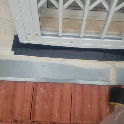 רעפים אדומים עם סרט איטום שחור ליד חלון