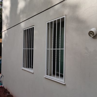 שני חלונות עם סורגים לבנים על קיר חיצוני