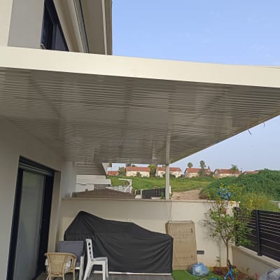 פרגולה מאלומיניום מחוברת לקיר חיצוני של בית