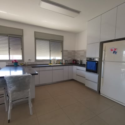 מטבח מאורגן עם ארונות לבנים ומקרר גדול