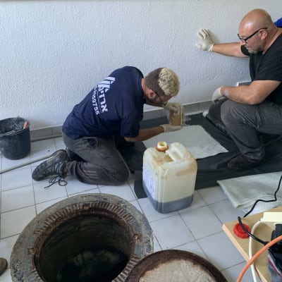 שני אנשים עובדים ליד פתח ביוב עם כלים וחומרים