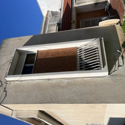 קיר חיצוני עם חלון וסורגים, כבלים חשמליים מחוברים