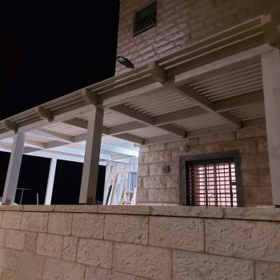 פרגולה מעץ צמודה לקיר אבן חיצוני