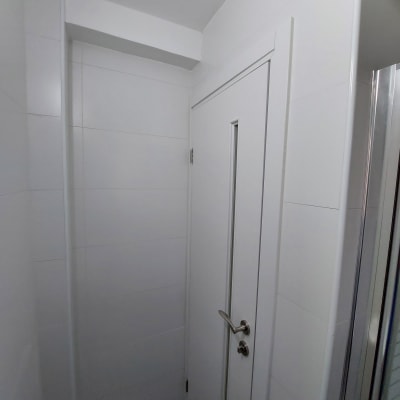 דלת לבנה חדשה עם ידית מתכת בחדר משופץ