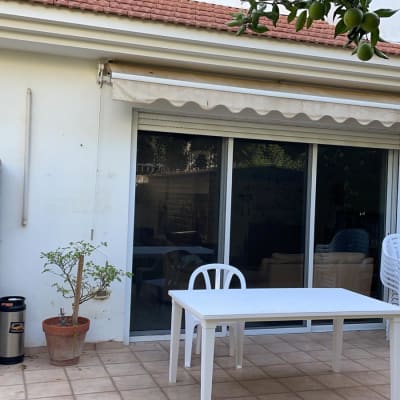 שולחן וכיסאות פלסטיק לבנים במרפסת עם דלת זכוכית