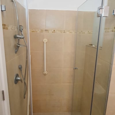 מקלחת עם דלת זכוכית, מוט אחיזה וראש מקלחת