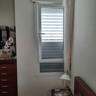 חלון אלומיניום עם תריסים סגורים בחדר שינה