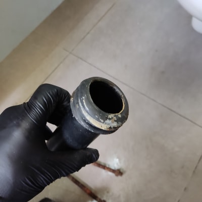 יד עם כפפה מחזיקה צינור שחור בחדר אמבטיה