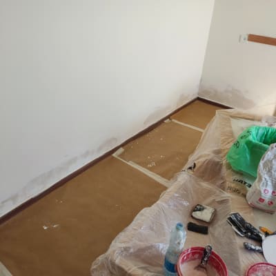 חדר עם קיר צבוע, כלים וחומרי צביעה על הרצפה