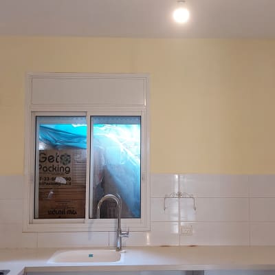 קיר צבוע בצבע צהוב בהיר מעל אריחים לבנים