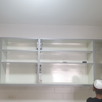 ארונות מטבח פתוחים עם אדם מתקין מדפים