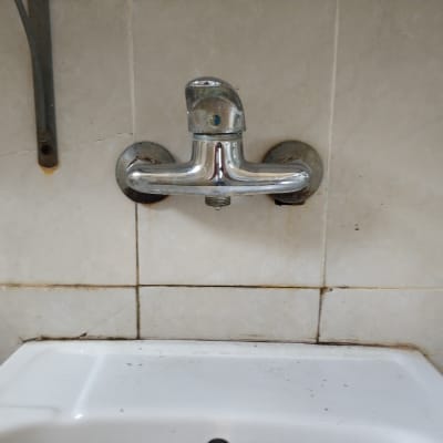 ברז מתכת מותקן על קיר אריחים לבנים