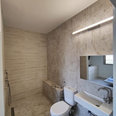 חדר אמבטיה משופץ עם אריחים חדשים וברזים מודרניים