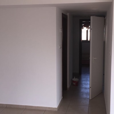 קיר צבוע בלבן עם דלי צבע ורוד על הרצפה