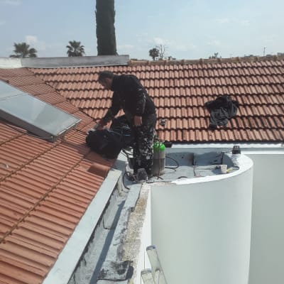 אדם עובד על גג עם כלים לאיטום