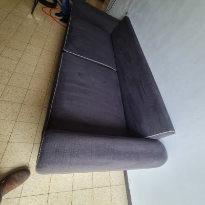 אדם מנקה ספה עם שואב אבק