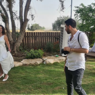 אישה בשמלה לבנה ליד צלם עם מצלמה